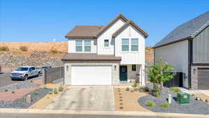 View of front of property featuring board and batten siding, stone siding, concrete driveway, and an attached garage