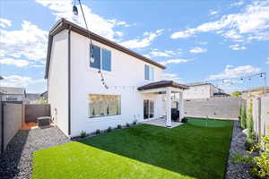 Rear view of property featuring a patio area, a putting area, a fenced backyard, and stucco siding