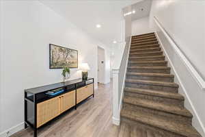 Stairs with wood finished floors and recessed lighting