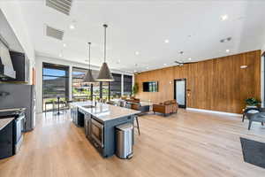 Kitchen with open floor plan, wood walls, hanging light fixtures, a spacious island, and stainless steel appliances