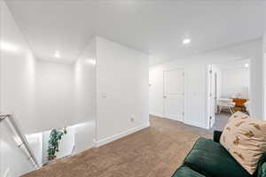 Living area featuring carpet flooring, recessed lighting, and an upstairs landing