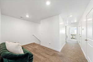 Living area with an upstairs landing, carpet flooring, and recessed lighting