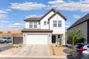 View of front facade featuring stone siding, board and batten siding, driveway, and an attached garage