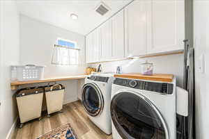 Laundry area with light wood finished floors, washing machine and clothes dryer, and cabinet space