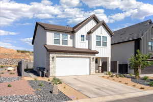 View of front of property with stone siding, an attached garage, board and batten siding, and driveway