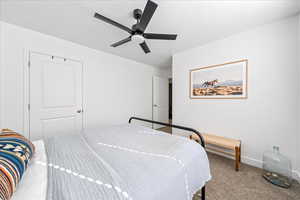 Carpeted bedroom with ceiling fan and baseboards