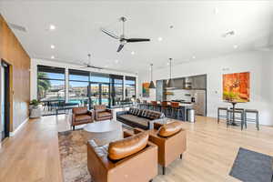 Living room with ceiling fan, light wood-style flooring, and recessed lighting