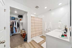 Full bath with a shower with shower curtain, recessed lighting, a walk in closet, vanity, and light wood-style flooring