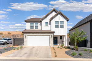 View of front facade featuring stone siding, board and batten siding, concrete driveway, and an attached garage