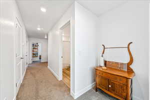 Hallway featuring light colored carpet and recessed lighting