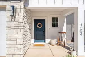 Doorway to property featuring stone siding and a porch