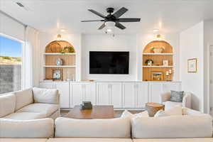 Living area with built in features, a ceiling fan, and wood finished floors