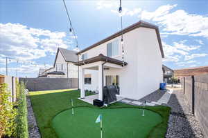 Back of property with a fenced backyard, a putting green, a patio area, and stucco siding