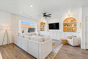 Living area with built in features, light wood finished floors, a ceiling fan, a textured ceiling, and recessed lighting