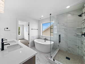 Bathroom with a freestanding bath, double vanity, a shower stall, tile walls, and recessed lighting