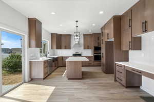 Kitchen featuring a kitchen island, decorative backsplash, pendant lighting, light wood-style flooring, and recessed lighting