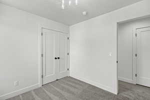 Unfurnished bedroom with carpet flooring, a closet, and a textured ceiling