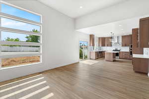 Unfurnished living room featuring light wood-style floors, recessed lighting, and a chandelier