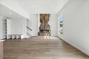 Unfurnished living room featuring a fireplace, light wood-style flooring, stairs, and recessed lighting