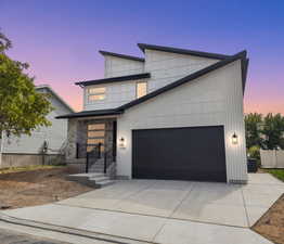 Modern home featuring driveway, an attached garage, board and batten siding, and stone siding
