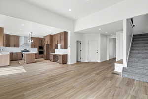 Unfurnished living room featuring stairway, recessed lighting, and light wood-type flooring