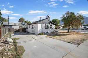 View of front facade featuring concrete driveway, stucco siding, and a chimney