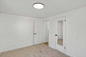 Unfurnished bedroom with carpet flooring and baseboards