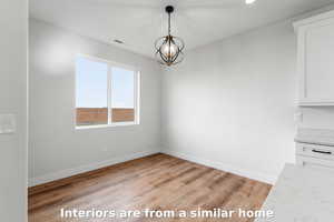 Unfurnished dining area with light wood-type flooring, a chandelier, and recessed lighting