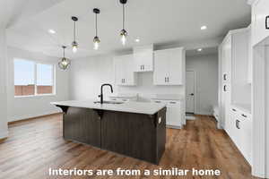 Kitchen with a kitchen breakfast bar, white cabinetry, a center island with sink, decorative light fixtures, and recessed lighting