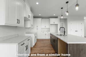Kitchen featuring white cabinetry, an island with sink, hanging light fixtures, recessed lighting, and light wood finished floors