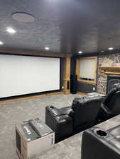 Cinema room featuring a textured ceiling, carpet flooring, a fireplace, and recessed lighting
