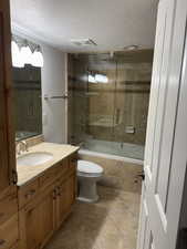 Bathroom with vanity, tiled shower / bath, a textured ceiling, and light tile patterned floors