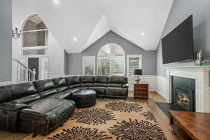 Living area with wood finished floors, a fireplace, recessed lighting, high vaulted ceiling, and a chandelier