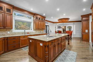 Kitchen featuring brown cabinetry, glass insert cabinets, recessed lighting, arched walkways, and light wood finished floors