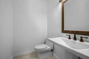 Half bath with light tile patterned floors and toilet