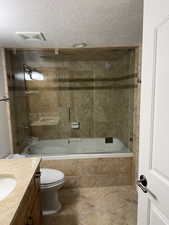 Bathroom with tiled shower / bath, a textured ceiling, vanity, and tile patterned flooring