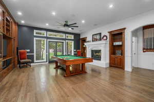 Playroom featuring recessed lighting, pool table, a warm lit fireplace, light wood finished floors, and ceiling fan