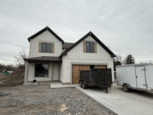 View of front facade featuring roof with shingles, concrete driveway, and board and batten siding