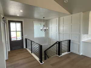 Entrance foyer with dark wood finished floors, recessed lighting, a barn door, and a chandelier