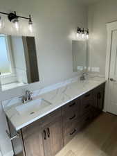 Full bath featuring double vanity and light wood-style flooring