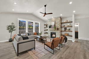 Living room featuring lofted ceiling, a ceiling fan, light wood finished floors, recessed lighting, and a fireplace