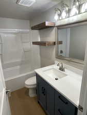 Full bathroom featuring a textured ceiling, dark wood-type flooring, vanity, and shower / tub combination