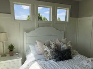 Bedroom featuring a decorative wall and wainscoting