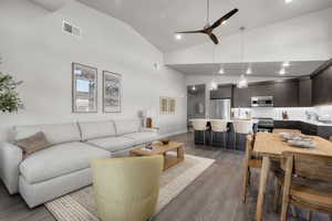 Living area with light wood-style floors, ceiling fan, high vaulted ceiling, and recessed lighting