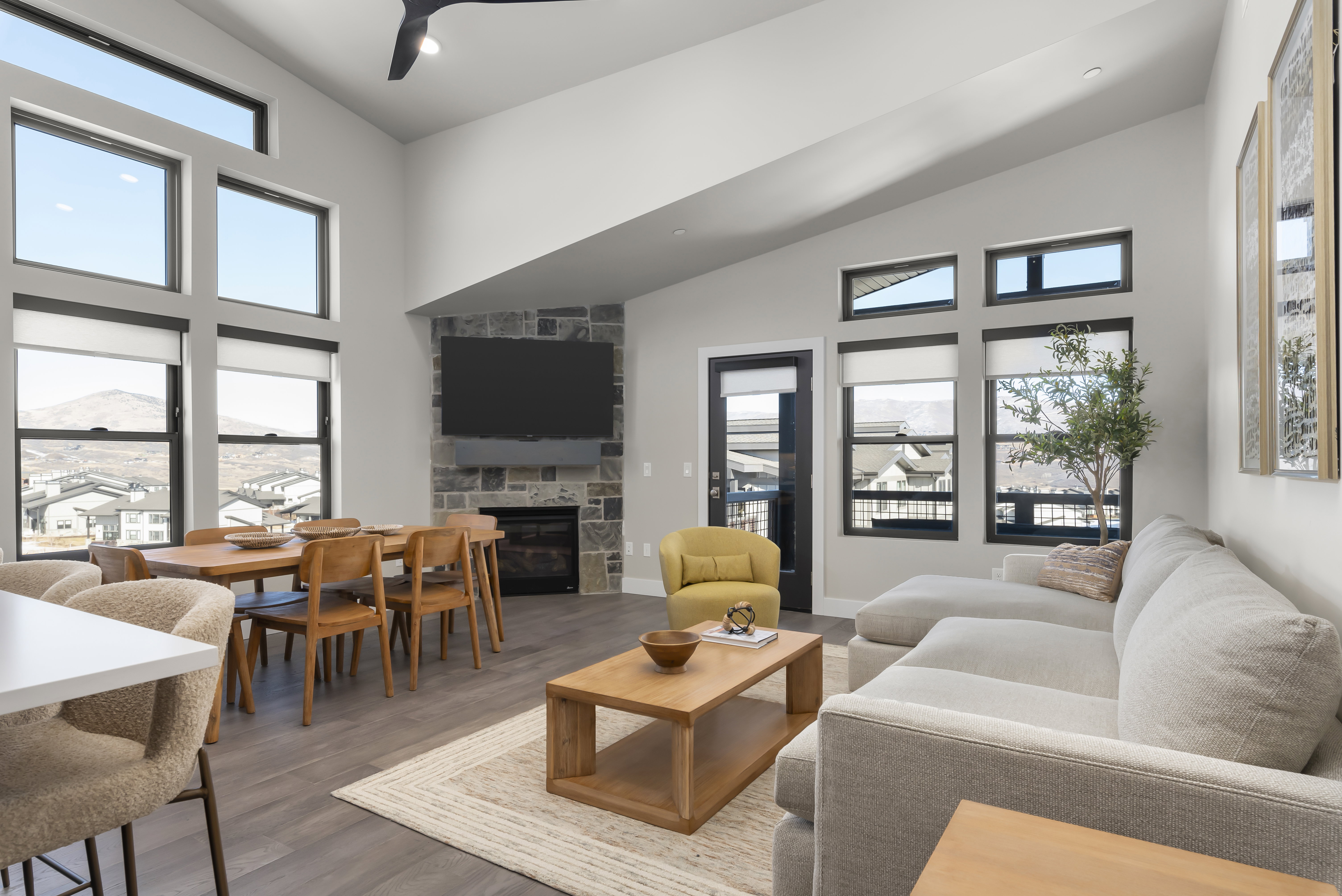 Living room featuring a fireplace, wood finished floors, high vaulted ceiling, and ceiling fan