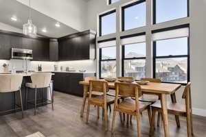Dining space with healthy amount of natural light, light wood finished floors, a high ceiling, and recessed lighting