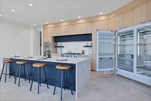 Kitchen featuring a breakfast bar, recessed lighting, decorative backsplash, modern cabinets, and a center island with sink