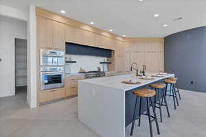 Kitchen featuring light brown cabinets, a breakfast bar, open shelves, modern cabinets, and recessed lighting