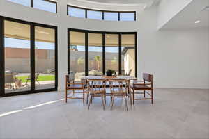 Dining room featuring a towering ceiling, light tile patterned flooring, and recessed lighting