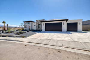 Contemporary house featuring concrete driveway, a standing seam roof, a garage, a metal roof, and stucco siding